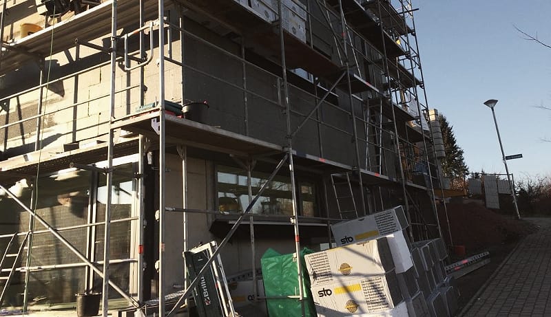 Gerüst an einem Neubau, an der Fassade werden Dämmplatten eines Wärmedämmverbundsystems angebracht
