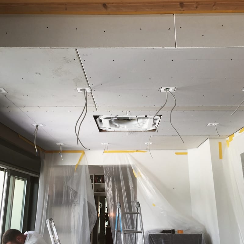 Neue Gipskartondecke während der Montage, Boden und Fenster abgedeckt